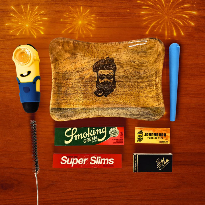 Minion smoking pipe with wooden rolling tray, rolling papers, roachbooks, cleaning brush and doobtube on a wooden surface.