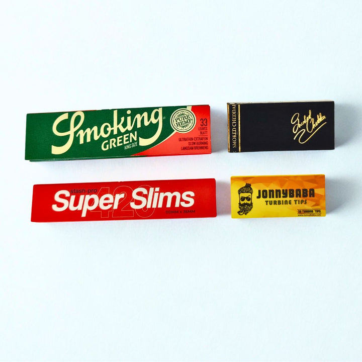 smoking green rolling paper, stash pro super slim rolling paper, smoked cheddar quote roachbook and jonnybaba turbine tip on white background