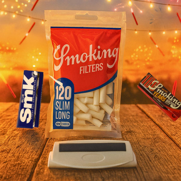 Smoking filters with cigarette rolling machine and cigarette papers on wooden surface and blurred lights in the background