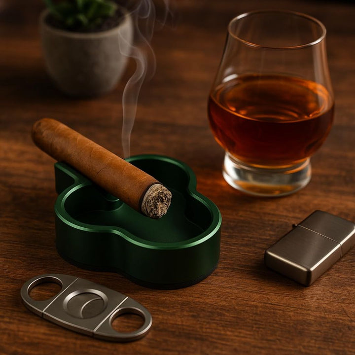 Cigar in a green holder with a glass of whiskey, lighter, and cutter on a wooden table.