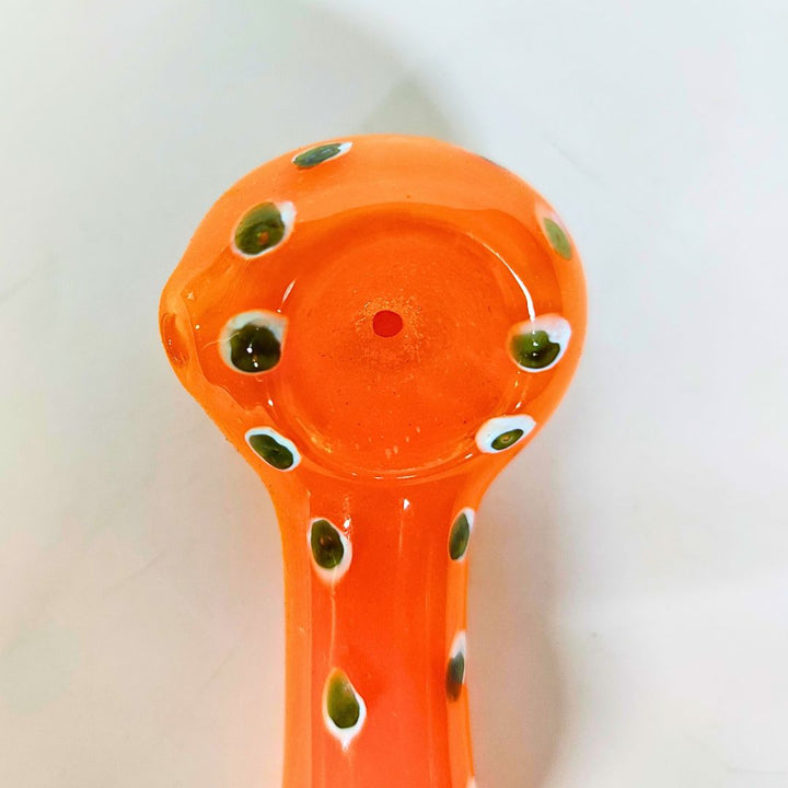 Orange glass pipe with green spots on a white background