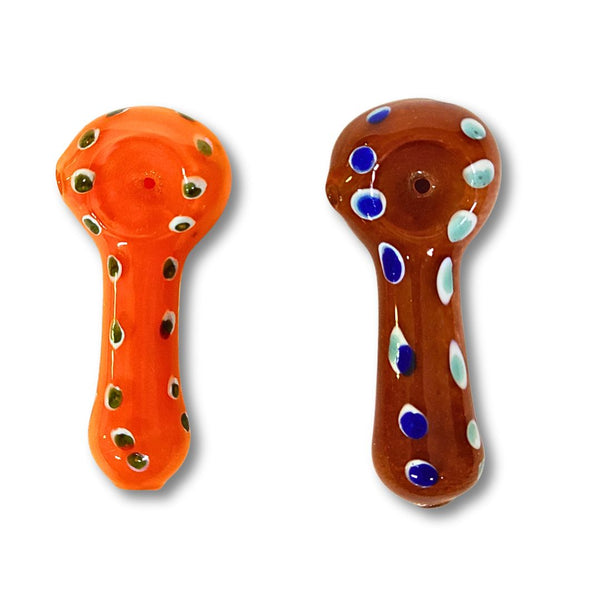 Two glass smoking bowls, one orange with green spots and one brown with blue and white spots, on a white background.