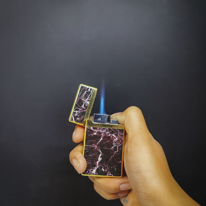 Hand holding a marbled lighter with a dark background