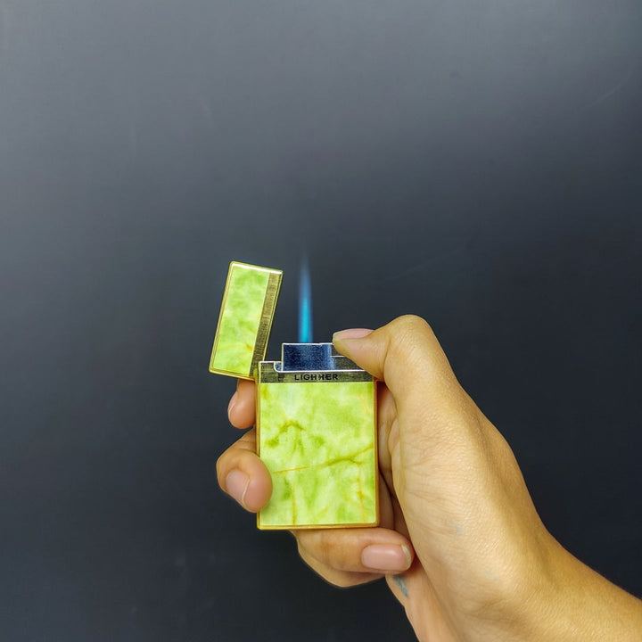 Hand holding a green and gold lighter with a dark background
