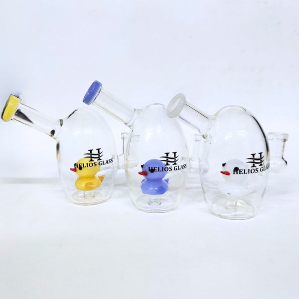 Glass smoking accessories with 'Helios Glass' branding and colorful duck decorations on a white background.