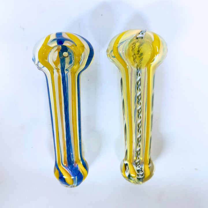 Two glass smoking pipes, one blue and yellow, the other clear with a pattern, on a white background.