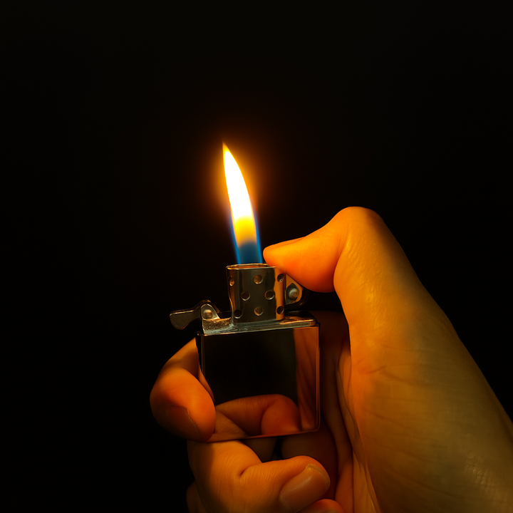 Hand holding a zippo lighter with a flame against a dark background