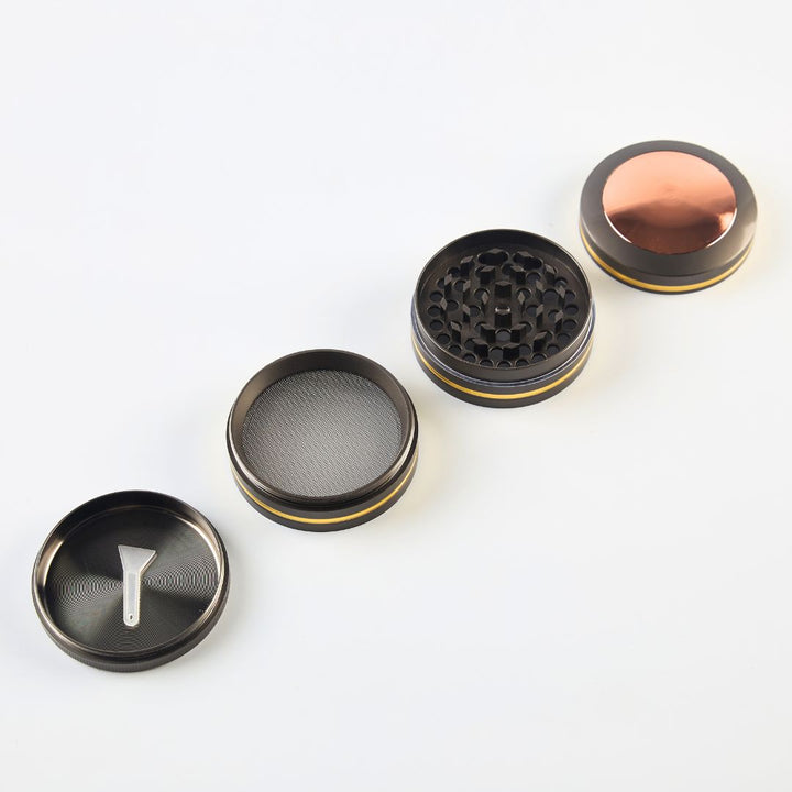 Set of four black and gold grinder parts on a white background