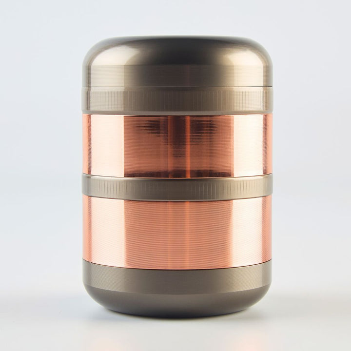 Two-toned metal grinder with rose gold and bronze finish on a white background
