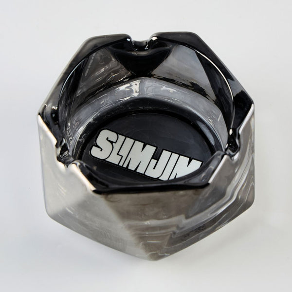 Hexagonal black ashtray with 'SLIMJIM' branding on a light gray background