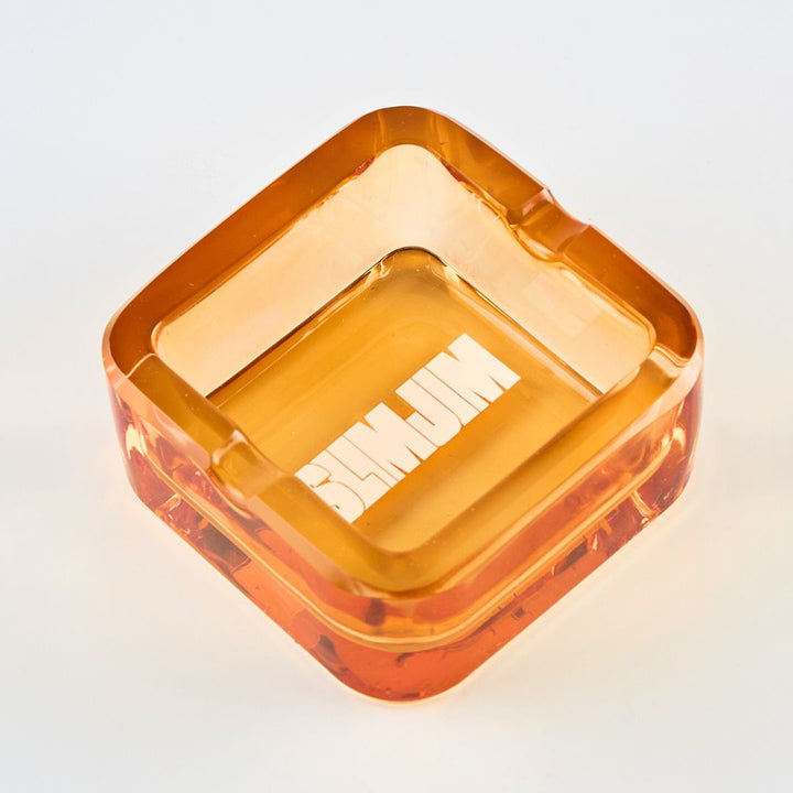 Square orange plastic ashtray with a lid on a light gray background