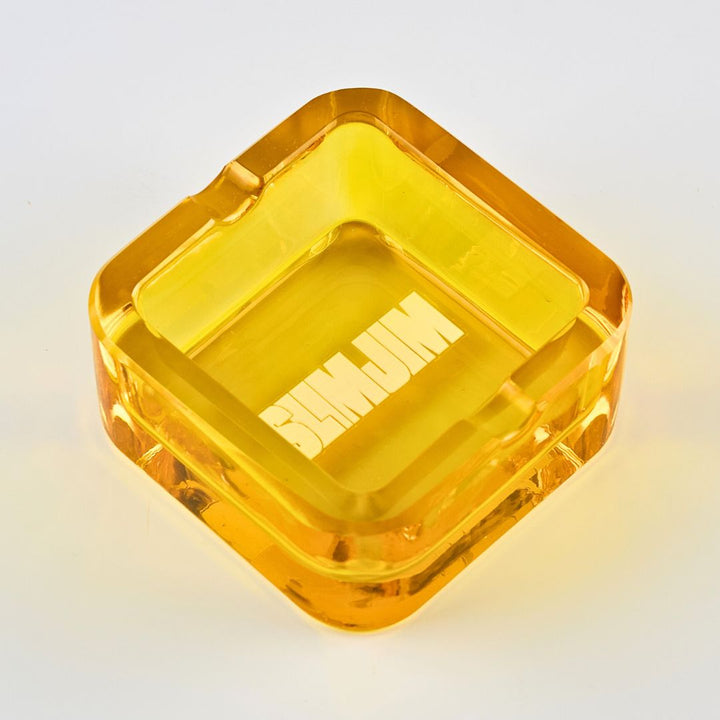 Clear yellow glass ashtray on a light gray background