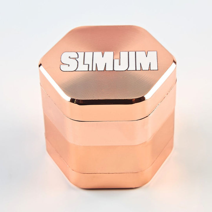 Rose gold herb grinder with 'SLIMJIM' branding on a light gray background