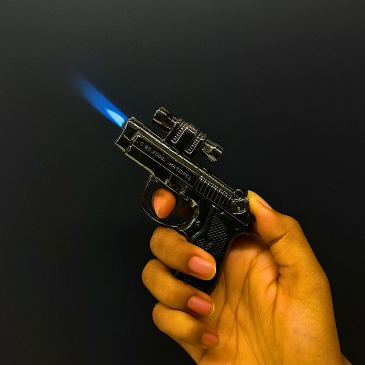 Hand holding a gun-shaped lighter with blue flame against a black background