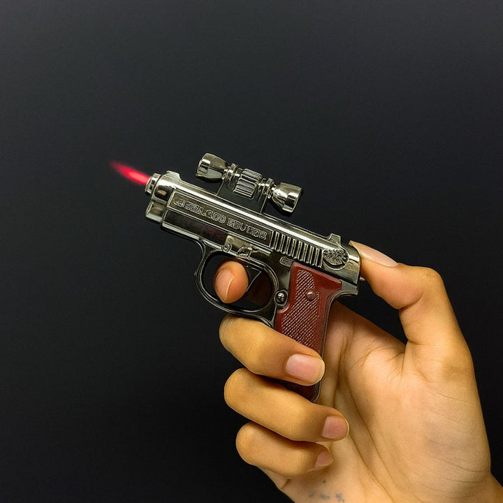 Hand holding a novelty lighter shaped like a gun with a black background